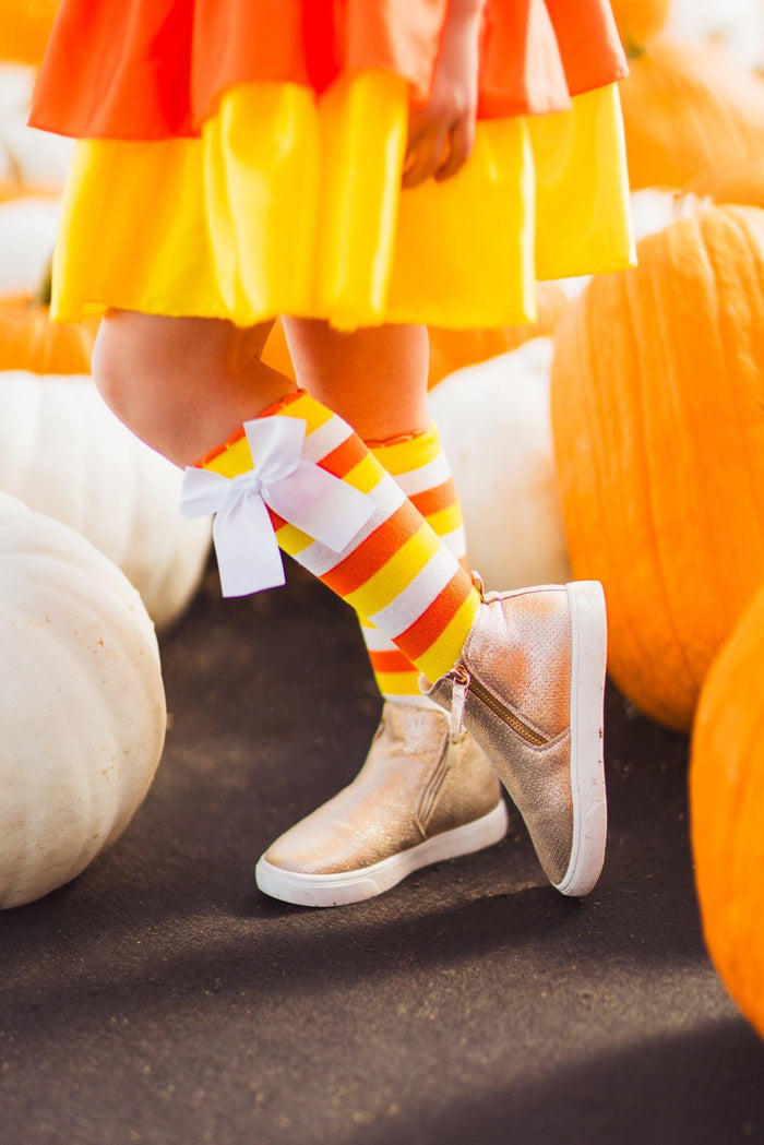 Candy Corn Witch Costume Knee High Socks - Small - Knee-high socks with yellow, orange, and white stripes worn with tan shoes and a yellow skirt.