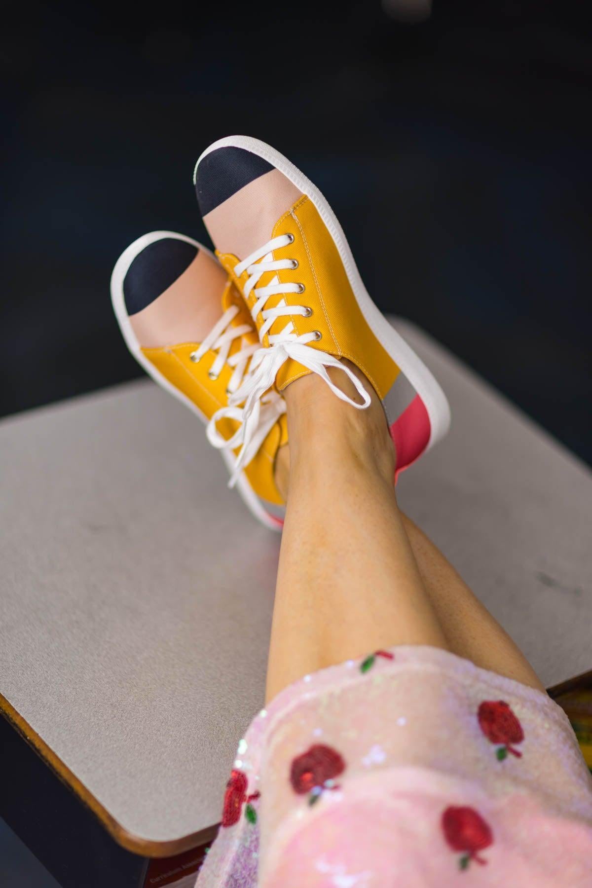 Pencil Sneakers - KIDS-8T - Yellow canvas sneakers with white laces, black toe caps, and pink heels worn with floral pajama pants.