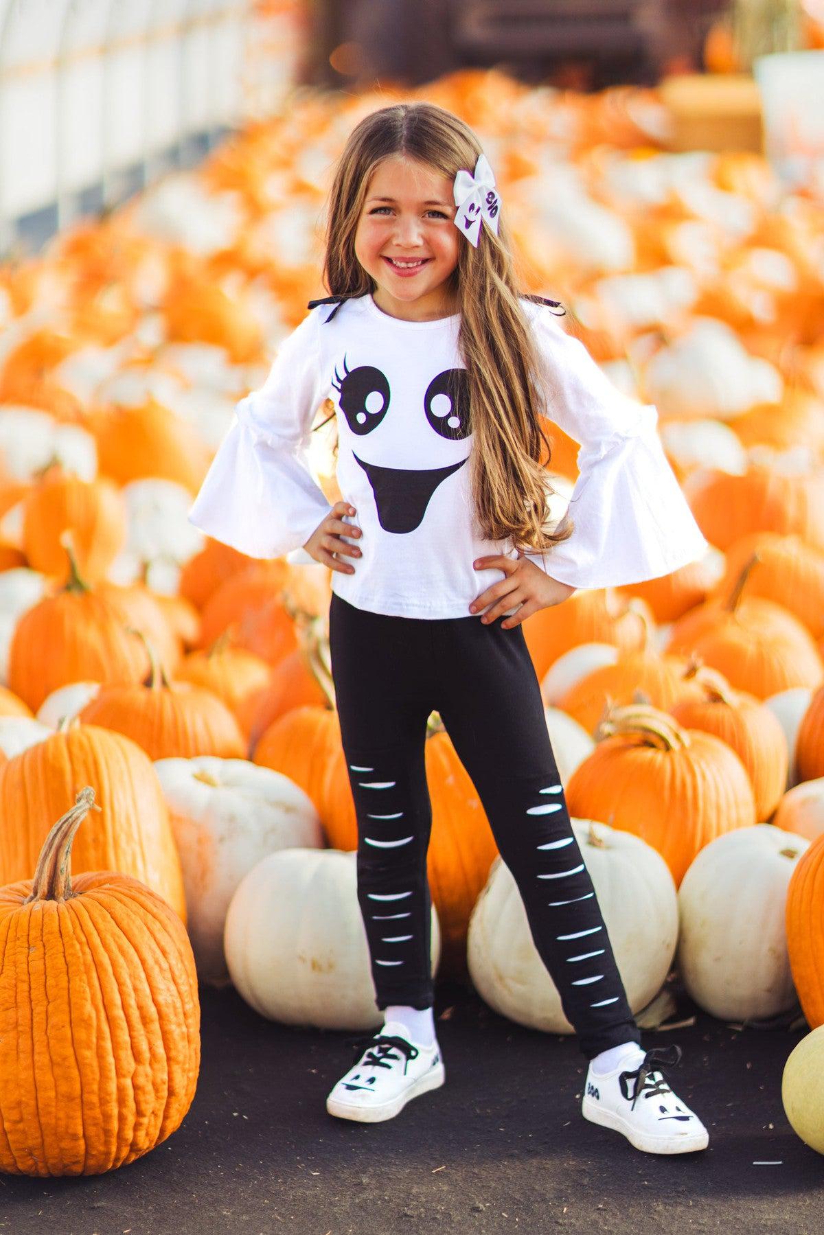 Black & White Ghost Distressed Legging Set - 3XS-6-12 Months - White long-sleeve shirt with ghost face graphic and black distressed leggings on girl with flower hair clip.