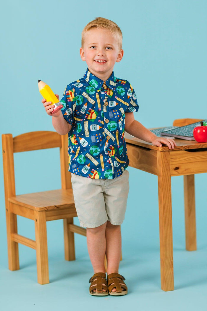 School Supply Star Button Down Top - Small-3T - Navy blue short-sleeve button-down shirt with colorful school supply prints worn by boy in beige shorts.