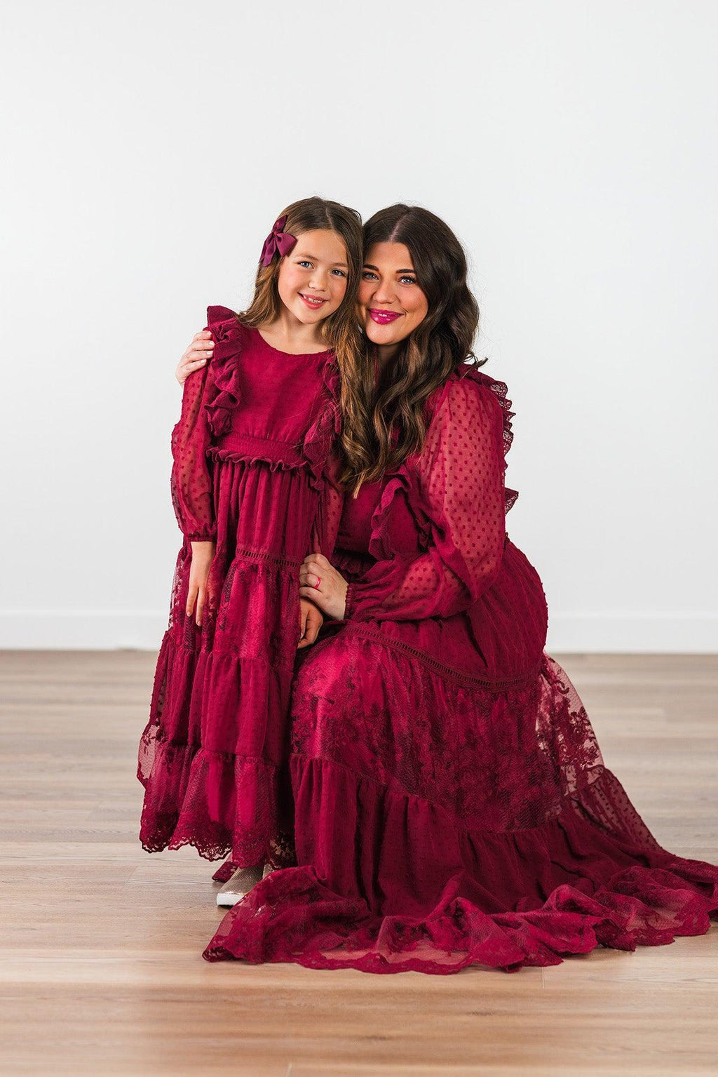 Mom & Me - Burgundy Swiss Dot Dress - CHILD-Small-3T - Burgundy Swiss dot dress with ruffled shoulders and tiered skirt on girl and matching long lace dress with ruffled sleeves.