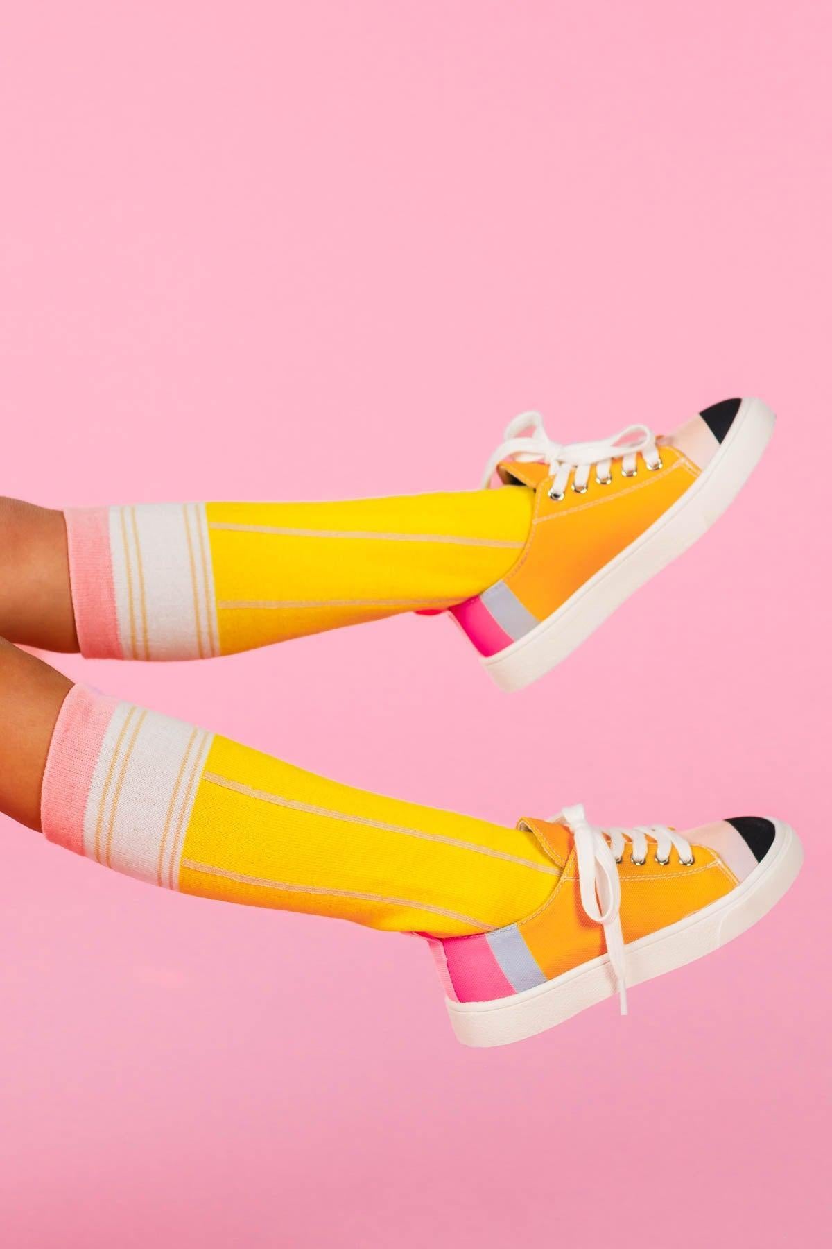 Pencil Knee High Socks - Default Title - Yellow knee-high socks with white and pink stripes paired with white sneakers on a pink background.