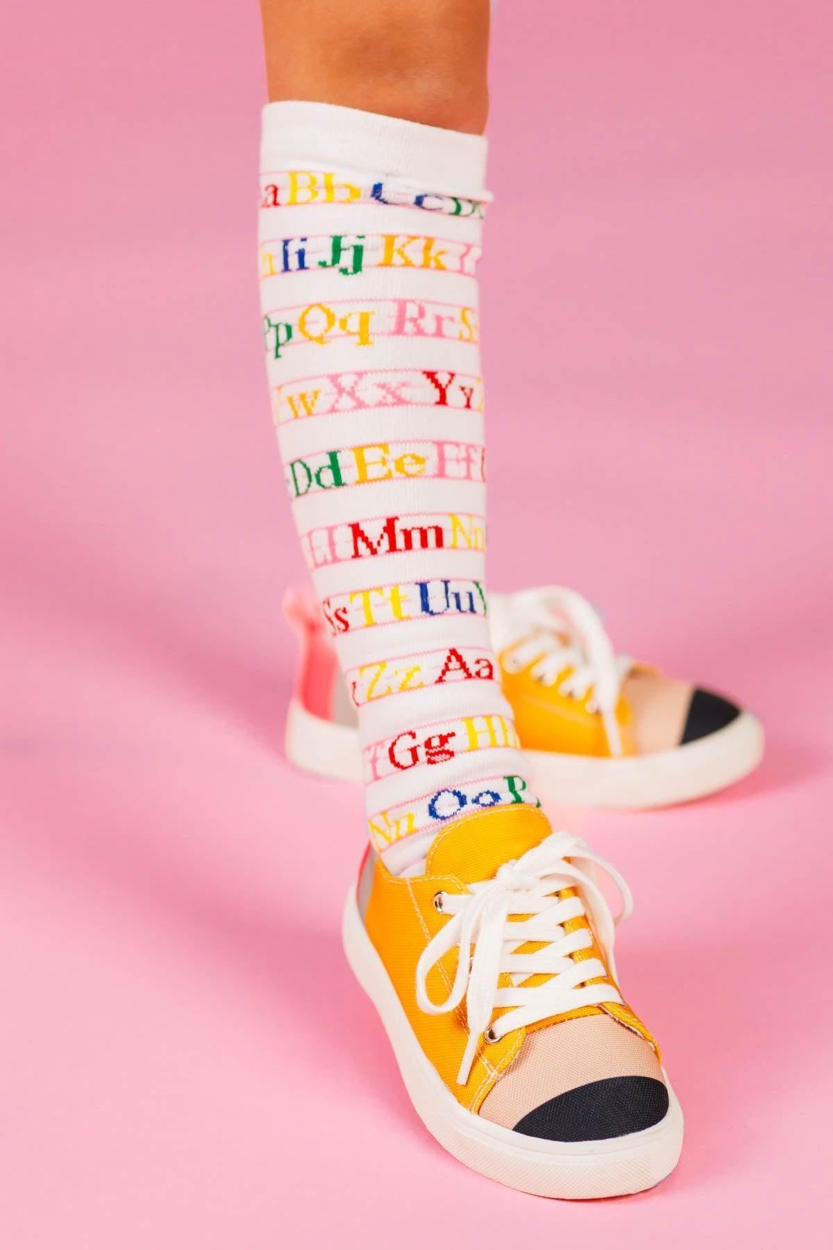 White Alphabet Knee High Socks - Default Title - White knee-high socks with colorful alphabet letters on a pink background.