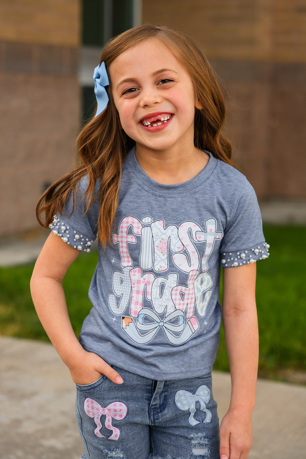 "Pre-K - Sixth Grade" Plaid Bow Denim Short Set - PRE-K / 2T - Blue short-sleeve shirt and matching denim shorts with pink and white plaid bow accents and "First Grade" text on shirt.