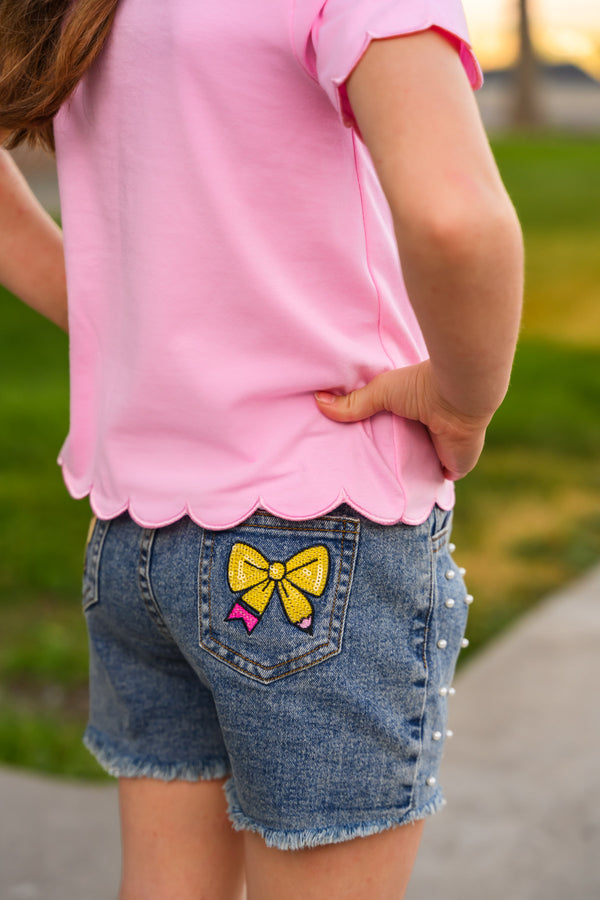 "Pre-K - Sixth Grade" Pink Pearl Denim Short Set - PRE-K / 2T - Pink short-sleeve top with scalloped hem paired with blue denim shorts featuring a yellow bow patch on the back pocket.