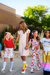 Pink School Supplies Jumpsuit - 3T - Girl wearing pink jumpsuit with colorful school-themed prints, short sleeves, and ruffle details.
