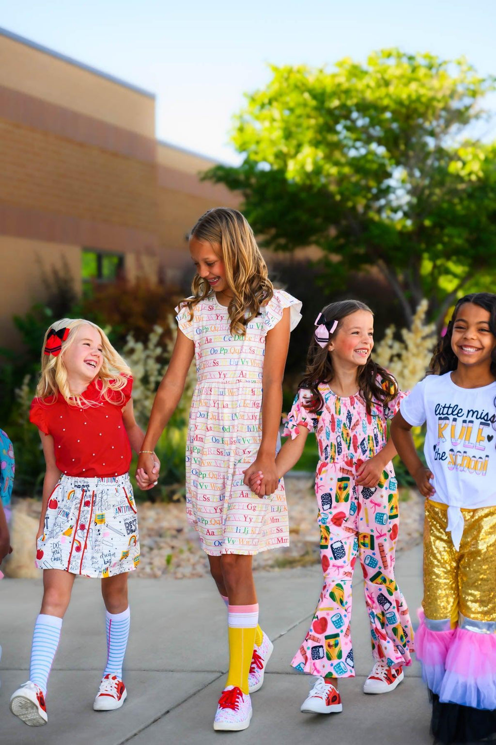 Pink School Supplies Jumpsuit - 3T - Girl wearing pink jumpsuit with colorful school-themed prints, short sleeves, and ruffle details.