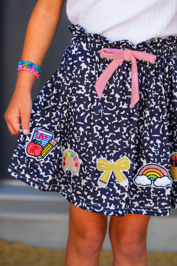 "Pre-K - Sixth Grade" Notebook Skirt Set - PRE-K / 2T - Navy blue knit skirt with white confetti print, pink drawstring, and colorful embroidered patches at hem.