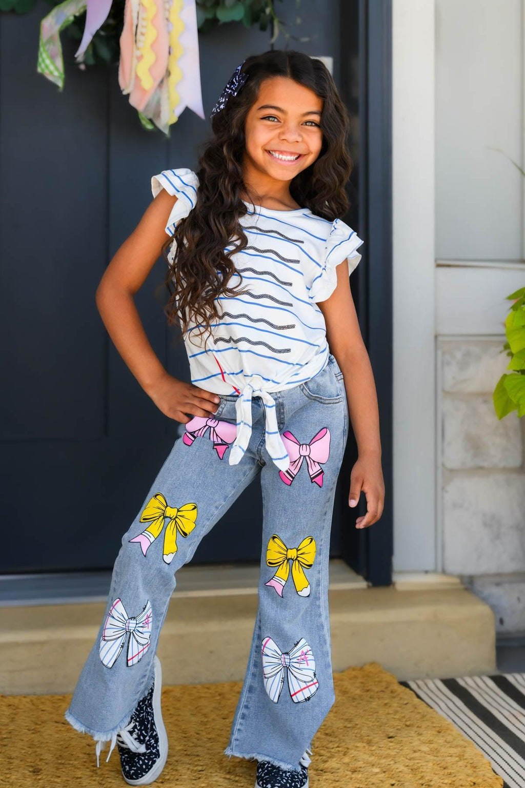 Notebook Bow Flare Denim Pant Set - 3T - Girl wearing light blue flare denim pants with colorful butterfly patches and a white ruffled sleeve striped top.