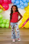 Red Apple Flare Denim Pant Set - 3T - Girl wearing red sleeveless polka dot top and light blue denim flare pants with red apple patches and white sneakers.