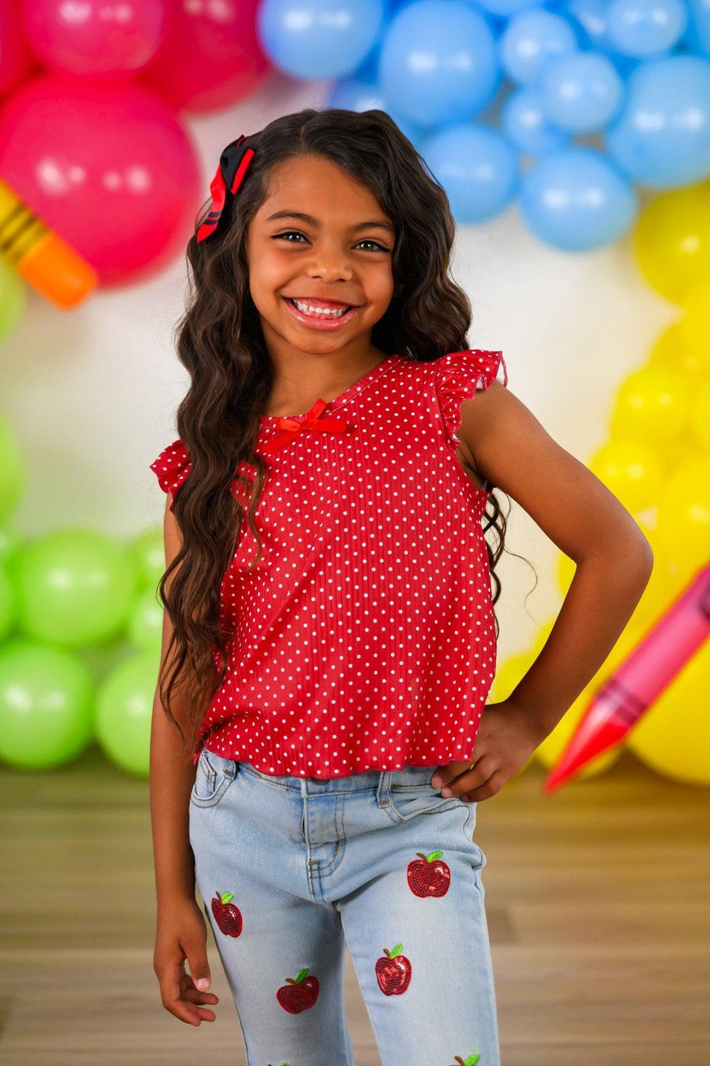 Red Apple Flare Denim Pant Set - 3T - Girl wearing a red sleeveless polka dot top with ruffle sleeves and light blue denim pants with red apple patches.