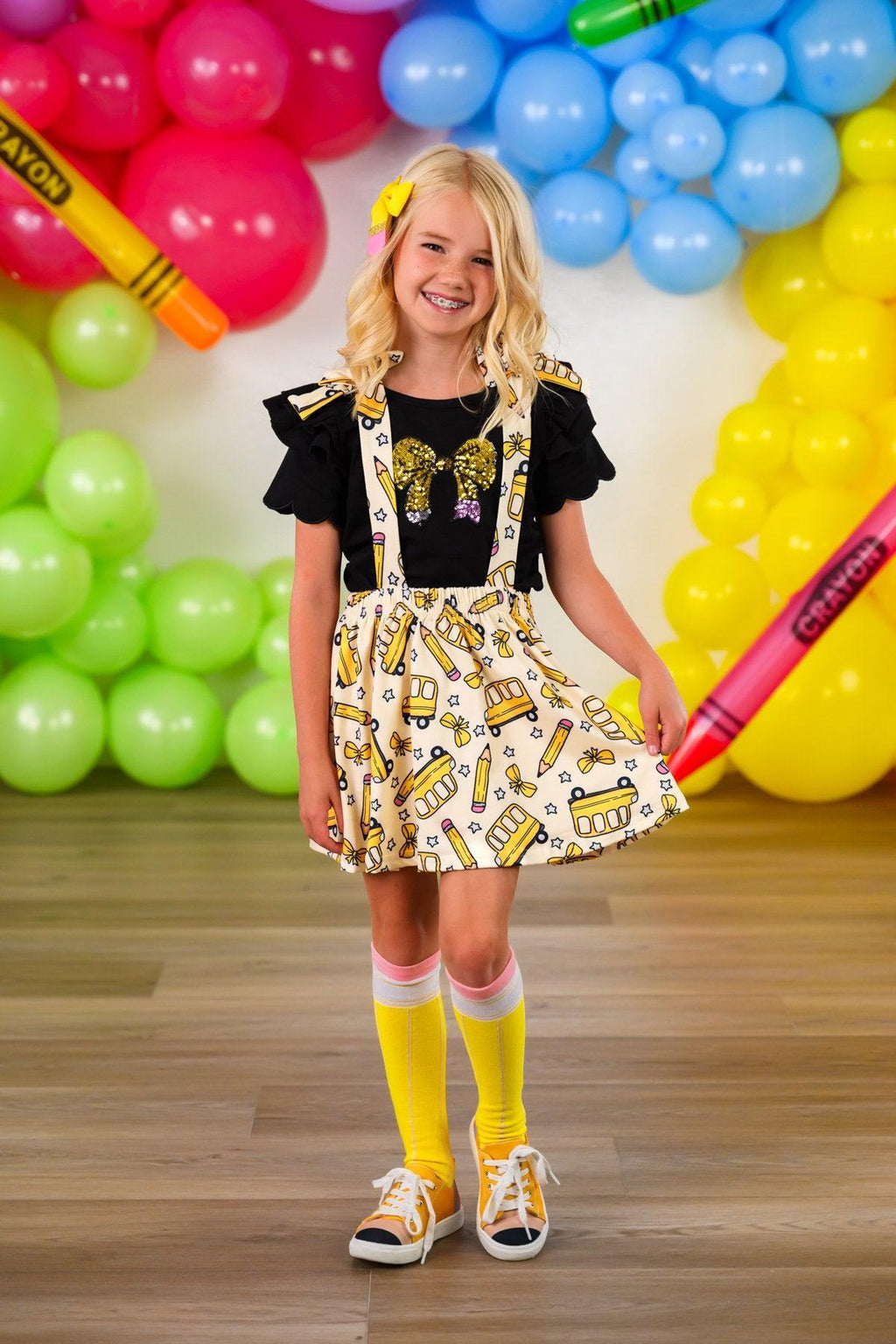 Pencil Bow Suspender Skirt Set - 3T - Black short-sleeve top paired with yellow pencil print suspender skirt, yellow knee-high socks, and white sandals.