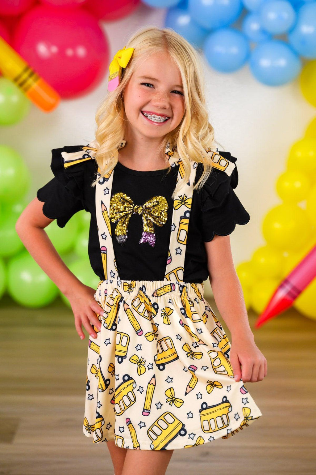 Pencil Bow Suspender Skirt Set - 3T - Yellow suspender skirt with pencil print and black bow details paired with black short-sleeve top with puffed sleeves.