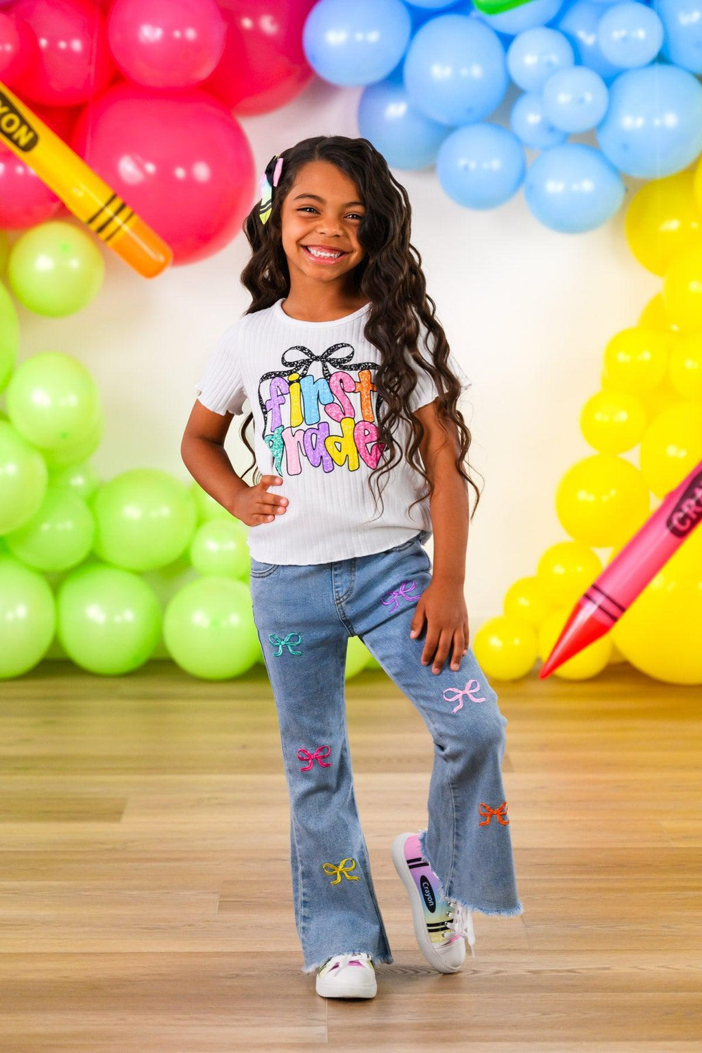 "Pre-K - Sixth Grade" Bow Denim Pant Set - PRE-K / 2T - Girl wearing light blue denim pants with colorful embroidered bows paired with a white graphic t-shirt and sneakers.