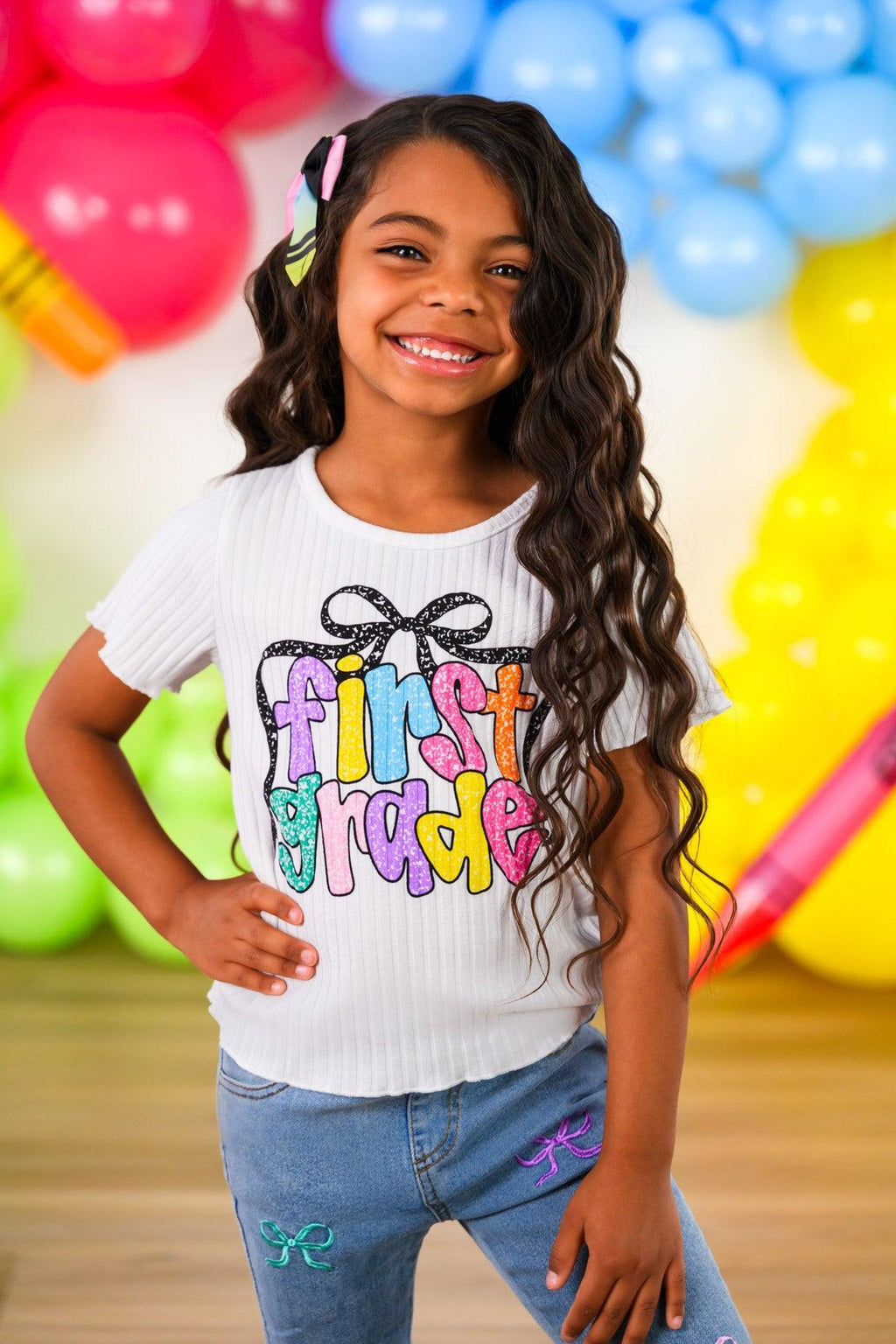 "Pre-K - Sixth Grade" Bow Denim Pant Set - PRE-K / 2T - Girl wearing white ribbed short-sleeve top with colorful "First Grade" text and black bow graphic, paired with light blue.