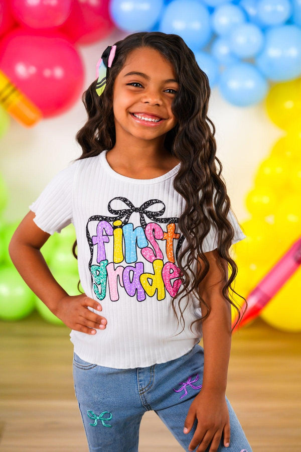 "Pre-K - Sixth Grade" Bow Denim Pant Set - PRE-K / 2T - Girl wearing white ribbed short-sleeve top with colorful "First Grade" text and black bow graphic, paired with light blue.