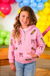 Mom & Me - Pink Pencils & Bows Pullover - 3T - Pink pullover with pencil and bow prints, long sleeves, and a front pocket worn by a smiling girl.