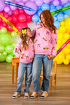 Mom & Me - Pink Pencils & Bows Pullover - 3T - Pink pullover with pencil and bow prints worn by mother and daughter, paired with blue jeans and sneakers.