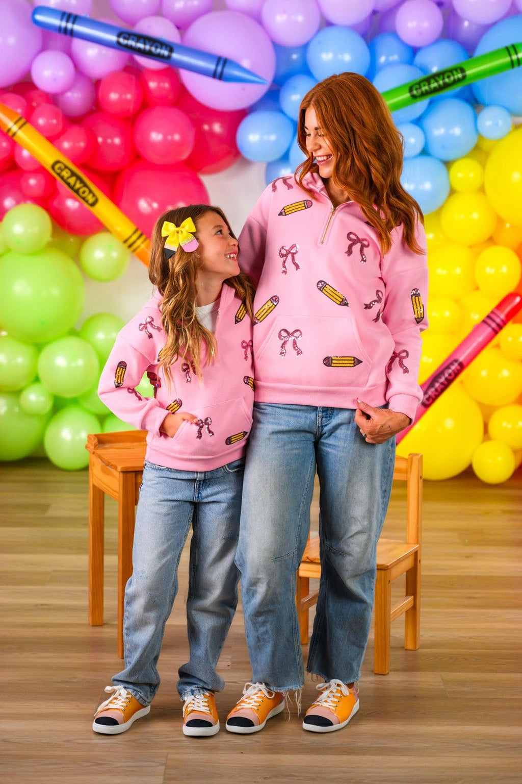 Mom & Me - Pink Pencils & Bows Pullover - 3T - Pink pullover with pencil and bow prints worn by mother and daughter, paired with blue jeans and sneakers.
