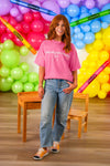 "I'm Literally Just A Teacher" Pink Top - MOM-XS - Soft pink short-sleeve cotton top with white "I'm Literally Just A Teacher" text, worn with light blue jeans and sneakers.