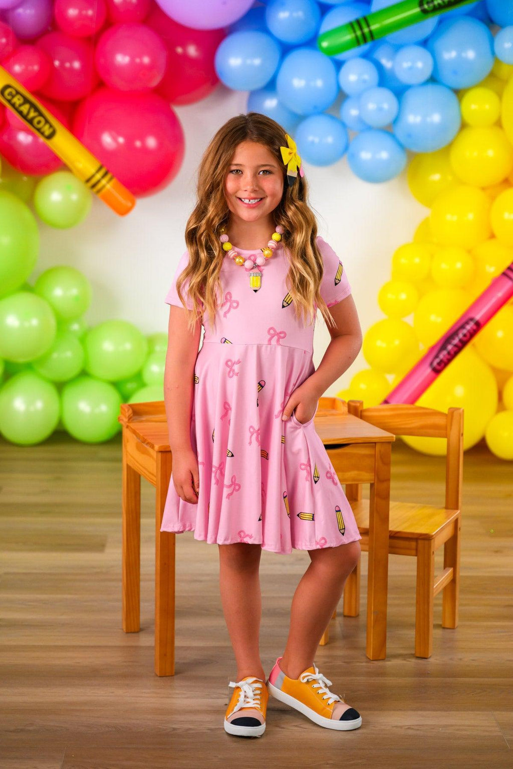 Mom & Me - Pink Pencil & Bow Dress - CHILD-3T - Pink sleeveless dress with pencil and bow print, flared skirt, worn with orange sneakers.
