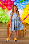 Mom & Me - Blue Pencil Dress - CHILD-3T - Light blue short-sleeve dress with gathered waist and small dark prints, worn with yellow casual sneakers.