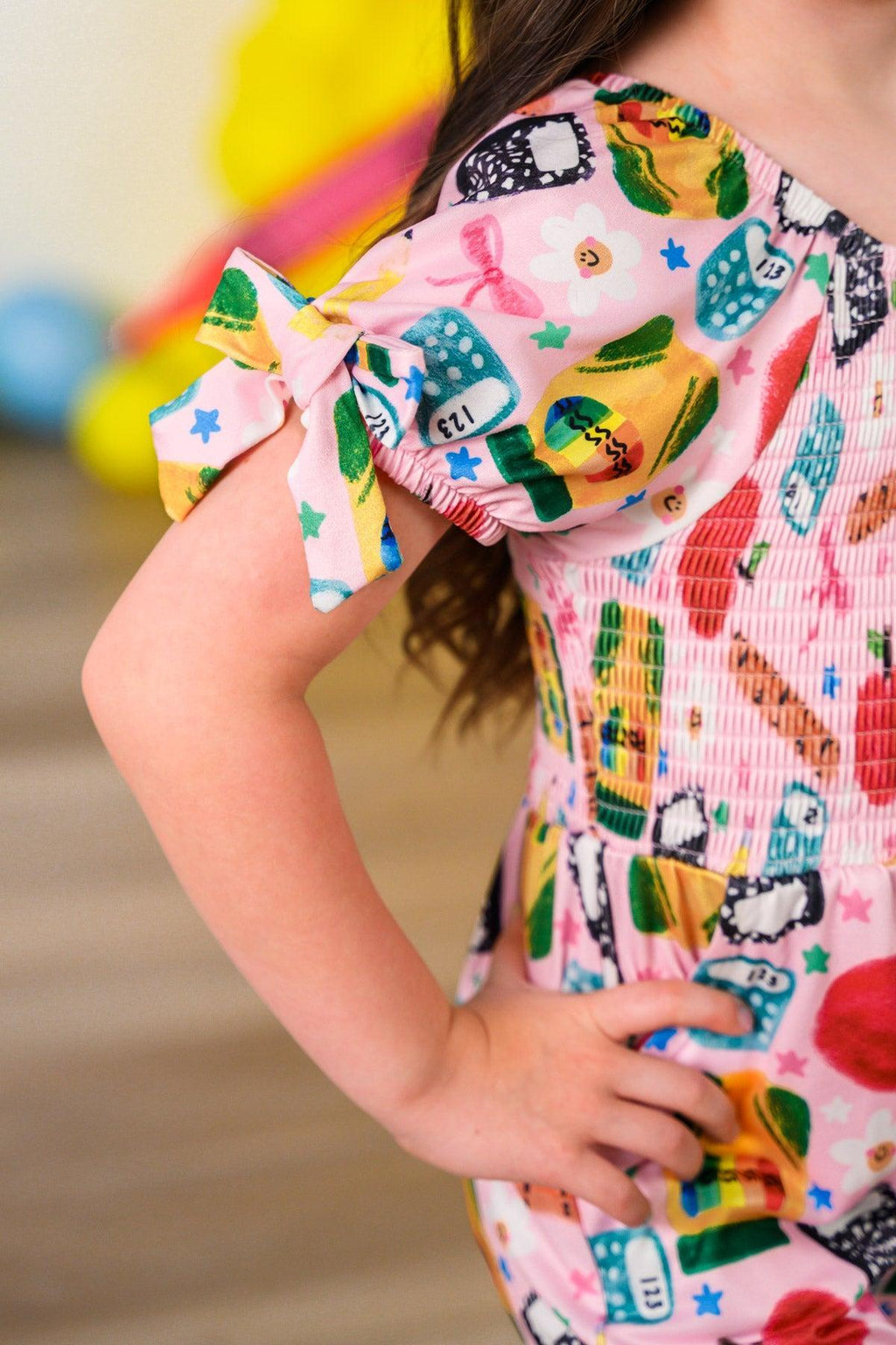 Pink School Supplies Jumpsuit - 3T - Pink jumpsuit with colorful school-themed print and puff sleeves tied in bows.