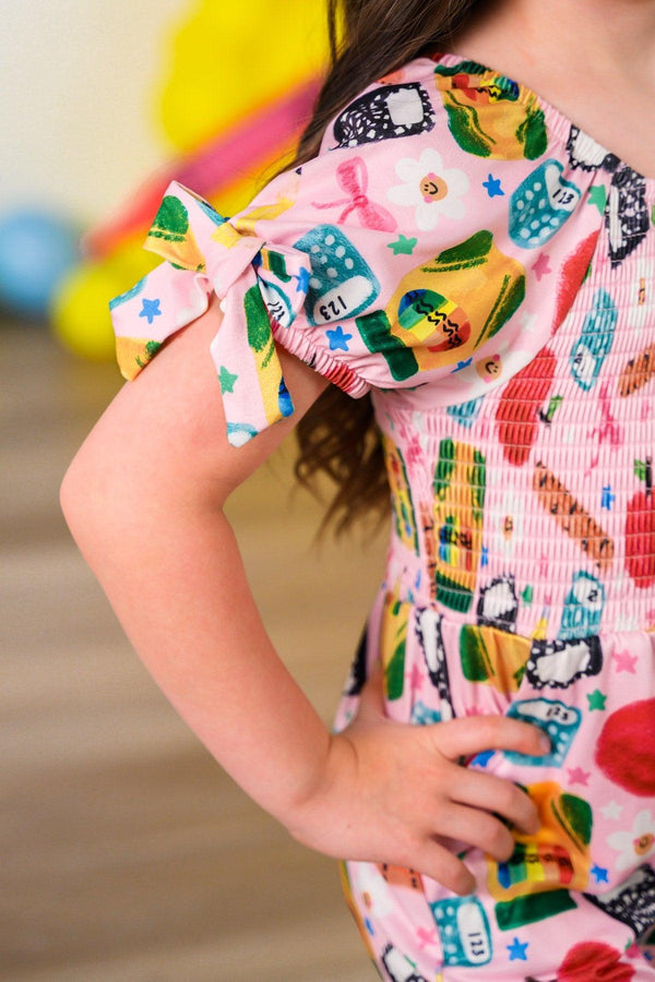 Pink School Supplies Jumpsuit - 3T - Pink jumpsuit with colorful school-themed print and puff sleeves tied in bows.