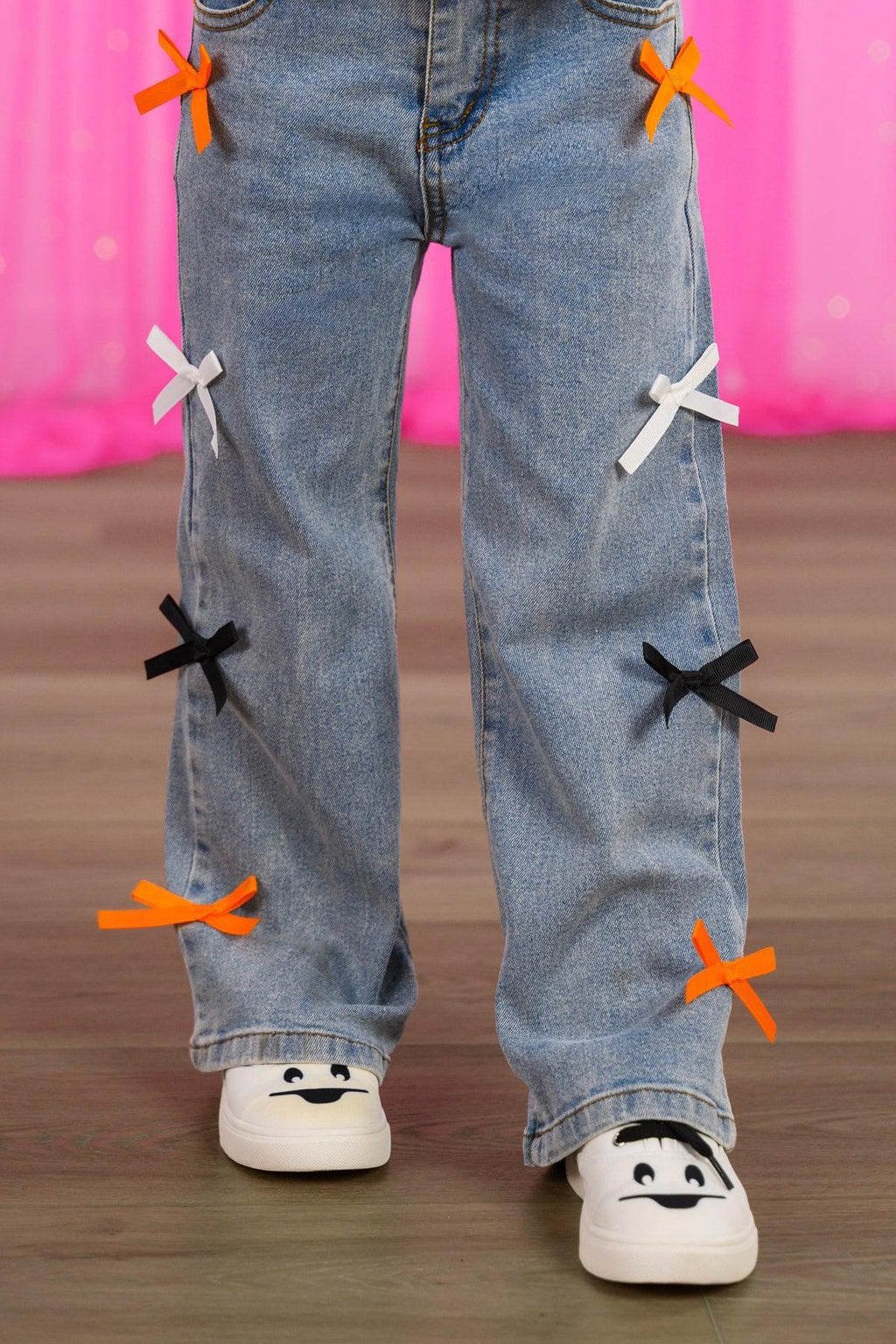 "Spooky Season" Bow Denim Pant Set - 6-12 Months - Light blue denim pants with colorful bow accents in orange, white, and black down the legs.