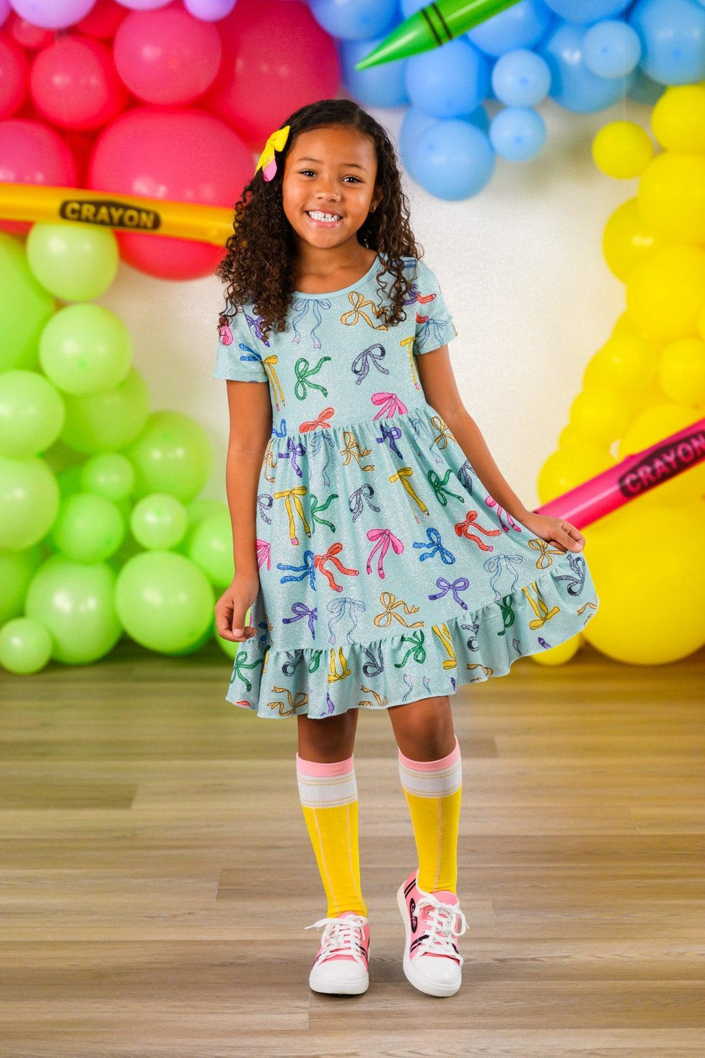 Mint Glitter School Bows Dress - 3T - Mint green short-sleeve dress with colorful glitter school bow patterns and a flared skirt worn by a smiling girl.