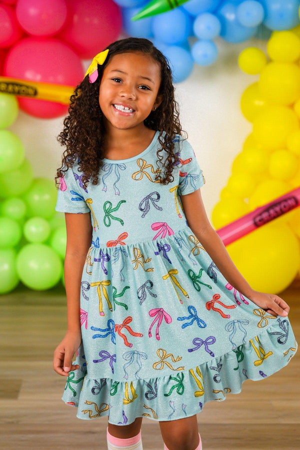 Mint Glitter School Bows Dress - 3T - Mint green dress with glittery school bow print, short sleeves, and ruffled hem worn by smiling girl.