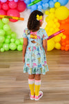 Mint Glitter School Bows Dress - 3T - Mint blue dress with colorful letter prints, short sleeves, open back bow detail, and ruffled hem worn by child with.