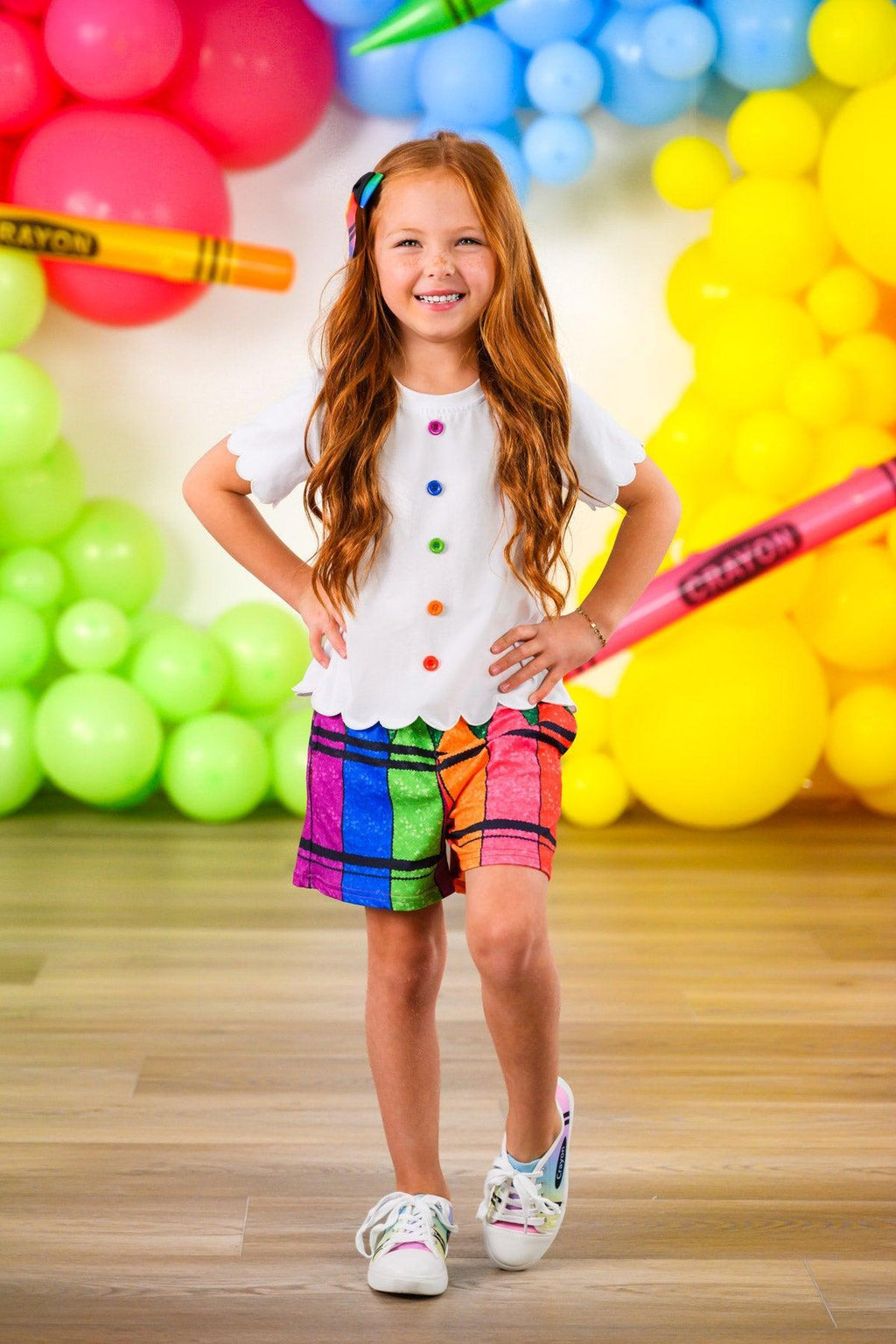 Crayon Short Set - 3T - Girl wearing a white short-sleeve top with colorful crayon dot buttons and vibrant, multicolored crayon-patterned shorts.