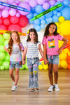 "Hello Pre-K - 6th Grade" Rainbow Denim Short Set - PRE-K / 2T - Girls wearing colorful casual outfits with denim shorts and graphic t-shirts, standing against a vibrant balloon backdrop.
