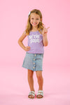 "Be The Good" Daisy Denim Skirt Set - 6-12 Months - Girl wearing a purple sleeveless top with "Be The Good" text and a light blue button-front denim skirt with scalloped hem.