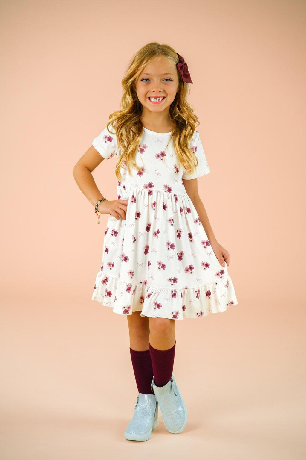 Pink Flowers & Bows Dress - 6-12 Months - White knee-length dress with pink floral print, short sleeves, and a gathered skirt, worn with maroon socks and light blue.