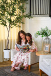 Mom & Me - Fuzzy Flower & Bow Pajamas - CHILD-6-12 Months - Matching cream-colored fuzzy pajamas with pink floral print and bow details on mother and daughter sitting together reading.