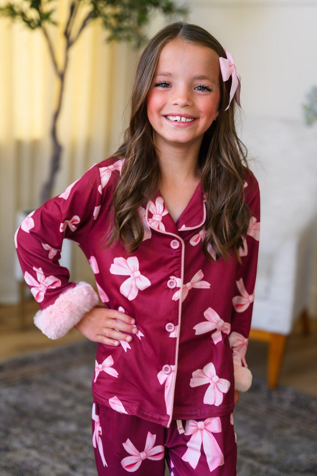 Mom & Me - Fuzzy Pink Bow Pajamas - CHILD-6-12 Months - Burgundy pajama set with pink fuzzy bows, button-up top with pink fuzzy cuffs, worn by smiling girl with pink hair bow.