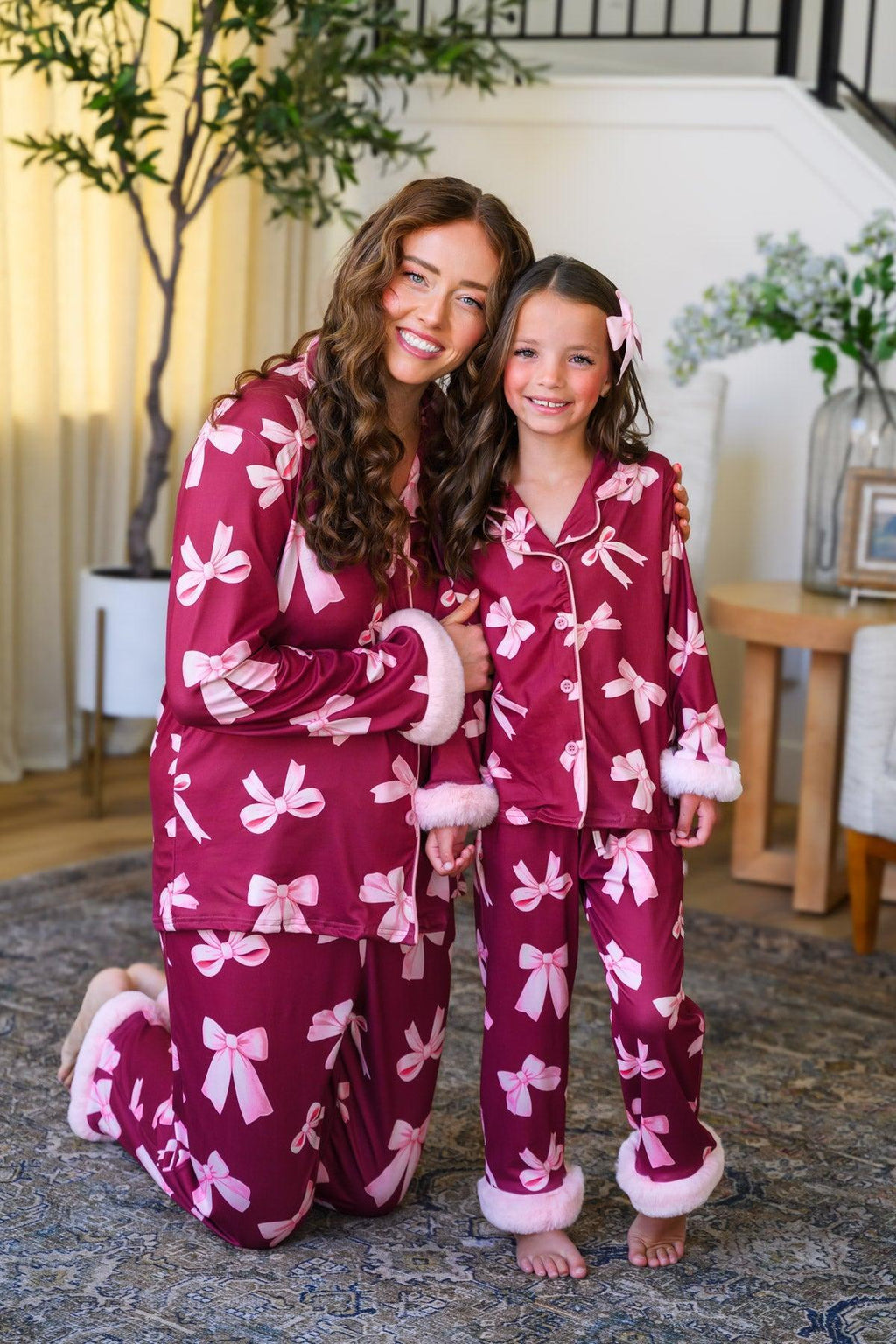 Mom & Me - Fuzzy Pink Bow Pajamas - CHILD-6-12 Months - Matching burgundy fuzzy pajamas with large pink bow patterns, featuring white trim cuffs on sleeves and pant legs, worn by.