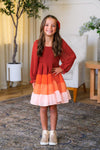 Mom & Me - Fall Ruffle Ombre Dress - CHILD-6-12 Months - Long-sleeve fall dress with tiered ruffle skirt in rust, orange, and pink ombre, worn by smiling young girl.
