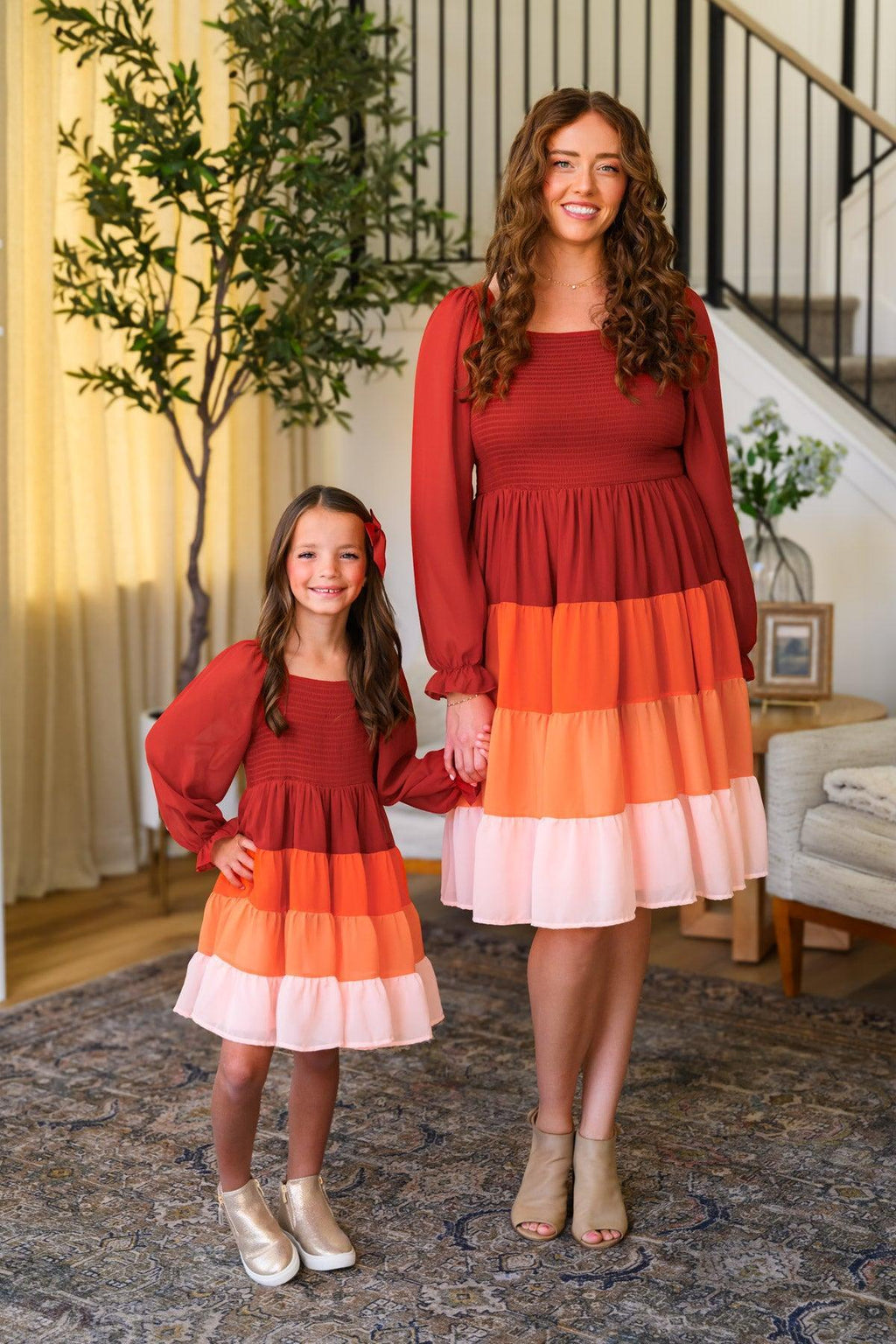 Mom & Me - Fall Ruffle Ombre Dress - CHILD-6-12 Months - Matching long-sleeve ombre ruffle dresses in rust, orange, and pink with tiered skirts, worn by woman and girl.
