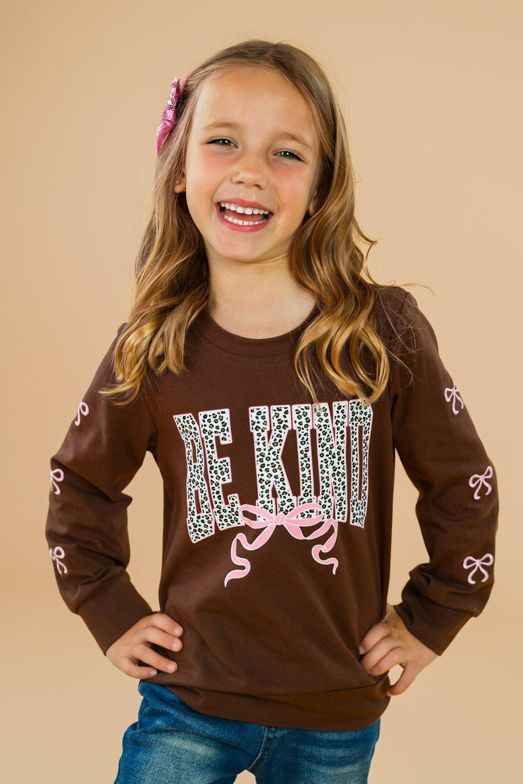 "Be Kind" Cheetah Denim Bell Bottom Set - 6-12 Months - Brown long-sleeve shirt with cheetah print "BE KIND" text and pink ribbon accents on sleeves and front.