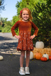 Rust Velvet Bow Dress - 6-12 Months - Rust-colored velvet dress with long sleeves and a bow accent at the waist, worn by a young girl outdoors.