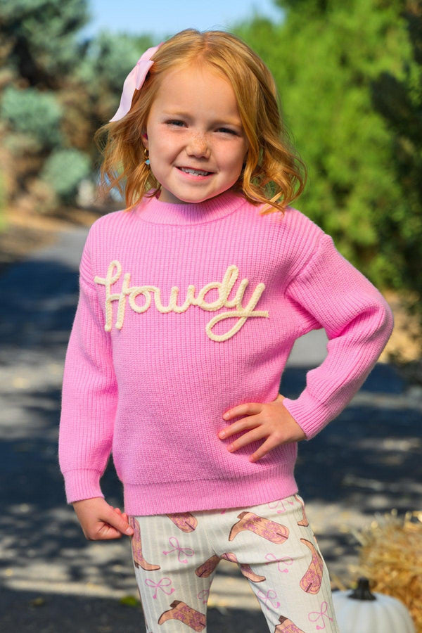 "Howdy" Pink Cowgirl Bell Bottom Set - 6-12 Months - Toddler girl wearing a bright pink knit sweater with "Howdy" in yellow cursive and white bell-bottom pants with pink heart.