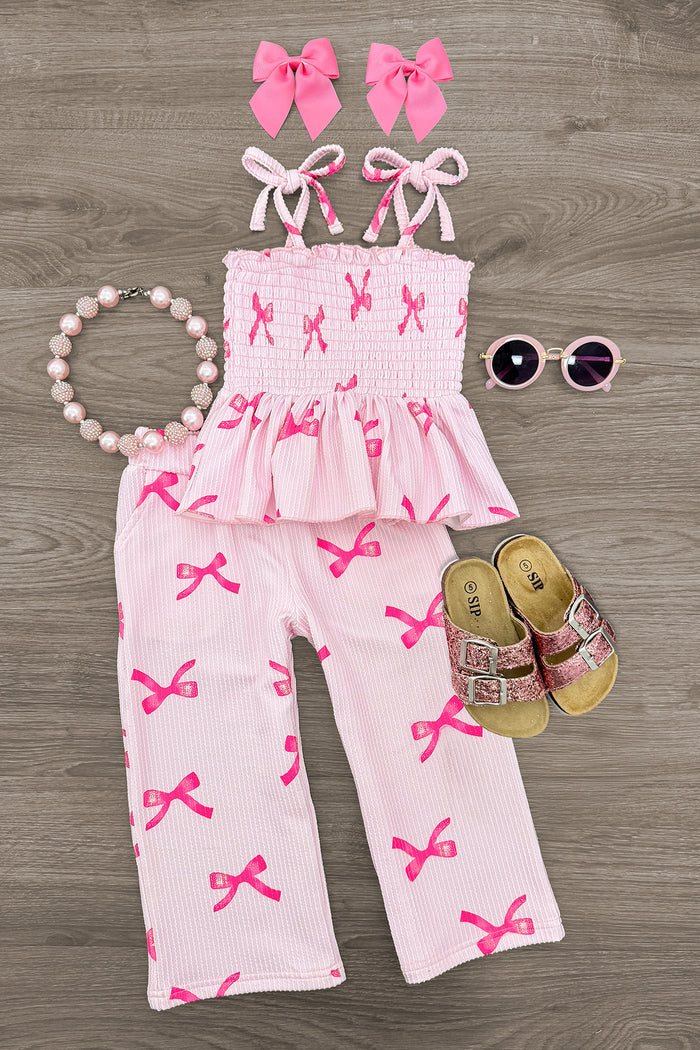Pink Bow Pant Set - 6-12 Months - Pink smocked sleeveless top and pants set with bow prints, paired with matching pink bow headbands, beaded necklace, gold.
