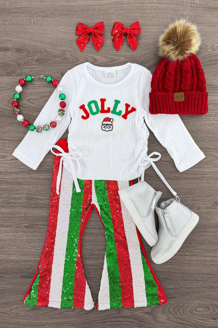 "Jolly" Chenille Patch Sequin Flare Set - 3XS-6-12 Months - White long-sleeve top with JOLLY sequin text, striped red and green flare pants, white boots, red knit hat with pom-pom, red .
