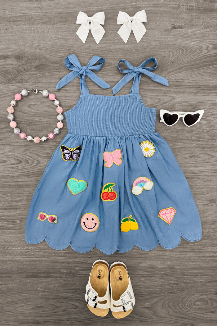 Summer Chambray Dress - 6-12 Months - Blue chambray sleeveless dress with scalloped hem and colorful embroidered patches, tied shoulder straps, paired with white.
