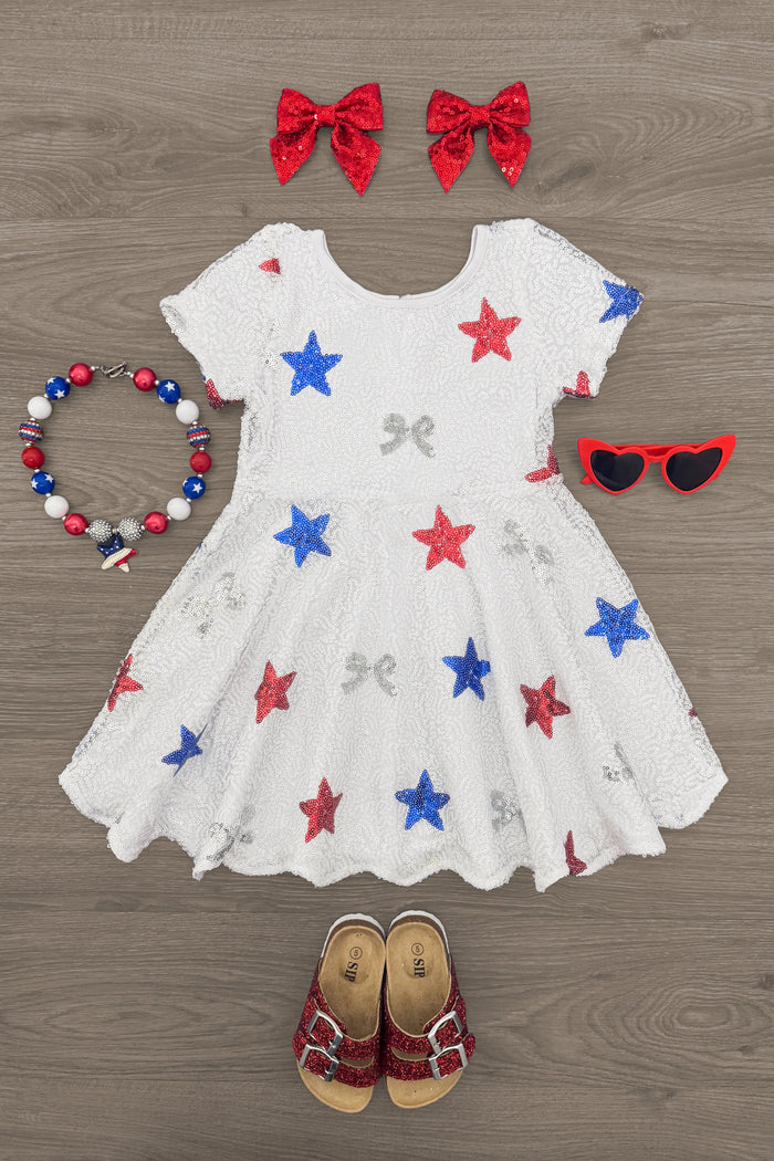 Sequin Bows & Stars Dress - 6-12 Months - White short-sleeve dress with red, blue, and silver star and bow sequins, paired with red bow clips, star necklace, red.
