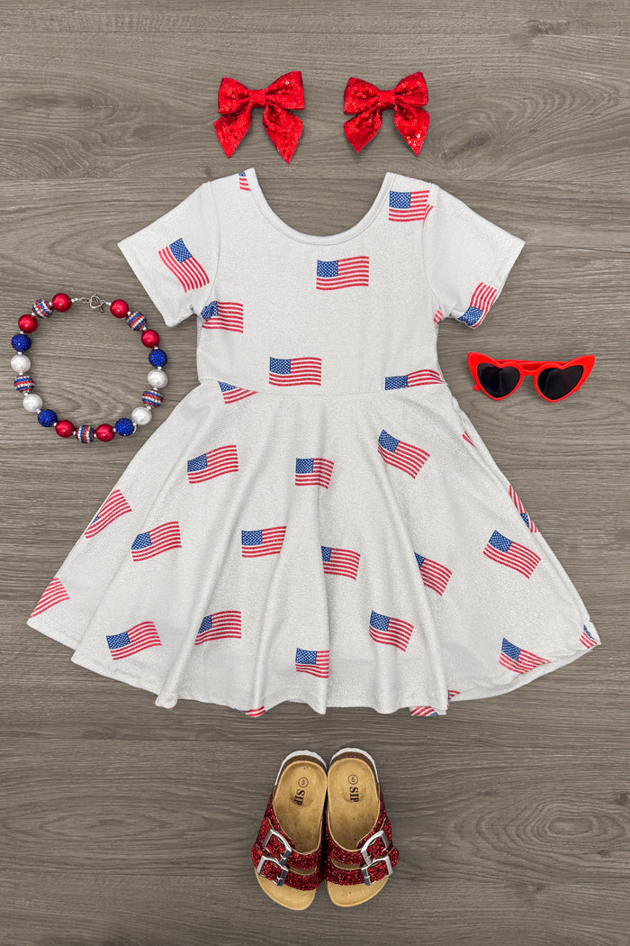 American Flag Glitter Dress - 6-12 Months - White toddler dress with repeated American flag print, paired with red bow clips, red heart-shaped sunglasses, patriotic.