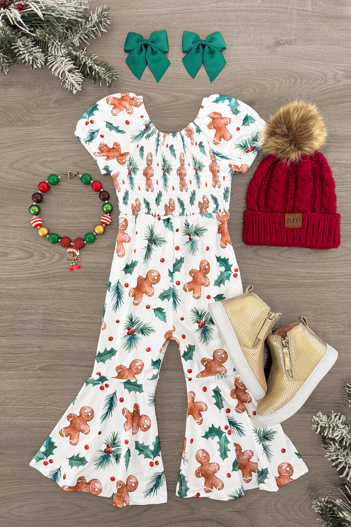 White Holly Gingerbread Jumpsuit - 3XS-6-12 Months - White jumpsuit with gingerbread print, puff sleeves, and flared legs paired with red knit hat with pompom, beige boots,.